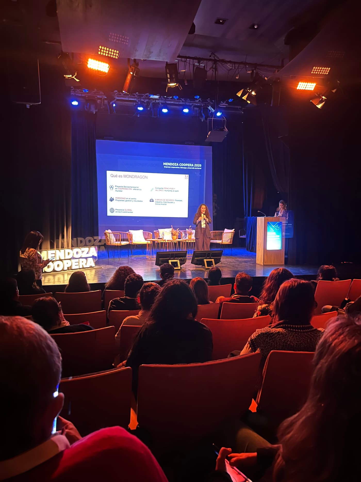 Packed Nave Cultural auditorium during Mendoza Coopera 2026, with the stage and screen at the far end